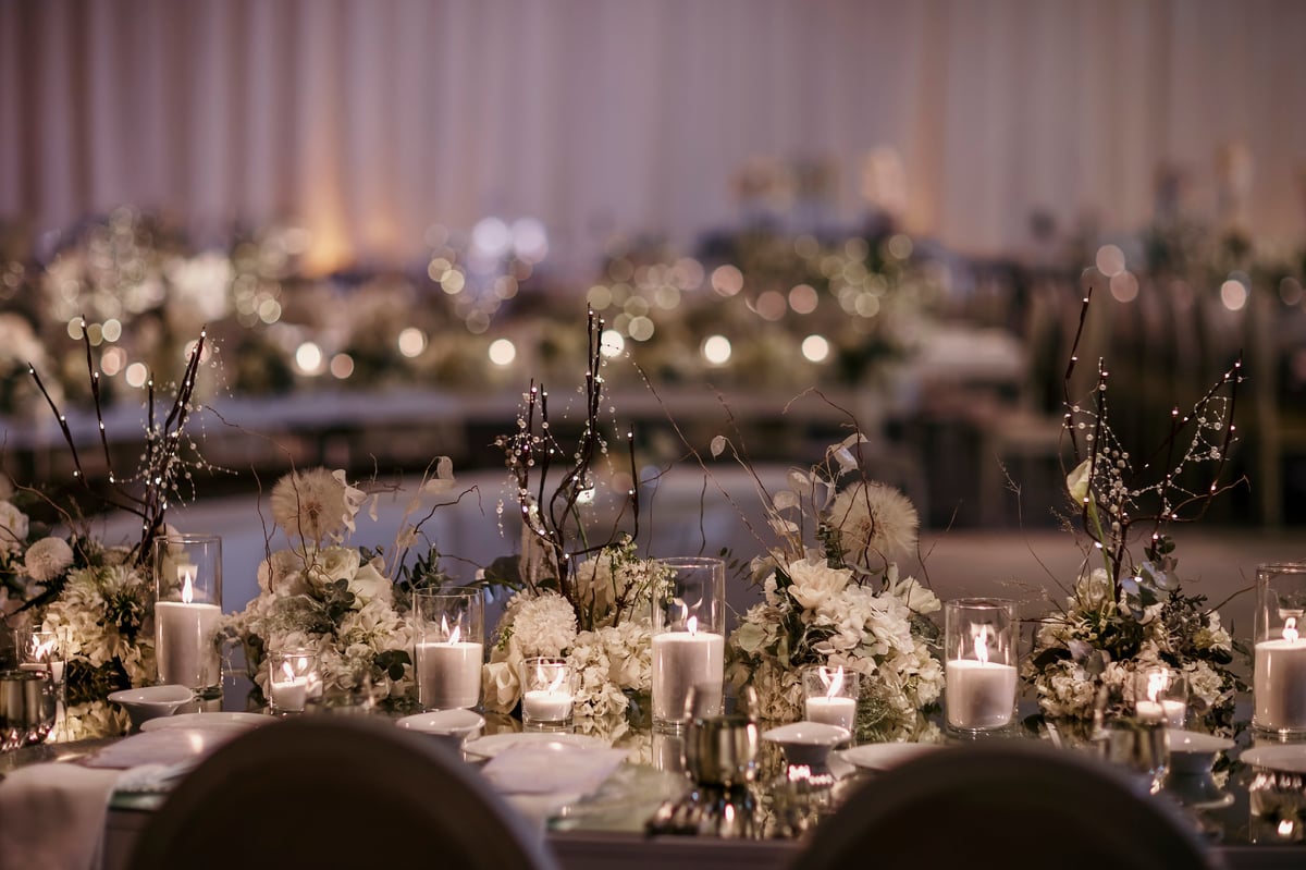 Elegant event table setting with soft candlelight and a delicate floral centerpiece against a warm ambient glow