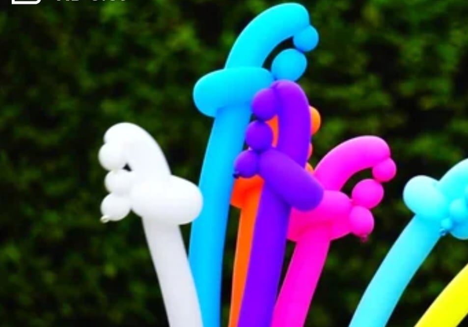 Colorful curved plastic tubes or pipes in white, cyan, purple, pink, and yellow stacked together against a blurred green background