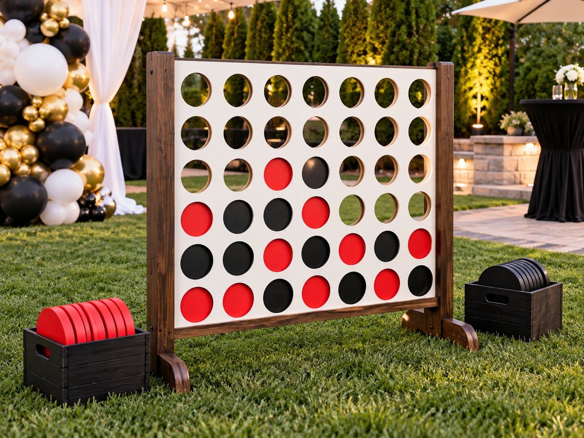 Giant Connect Four game set up on grass at an outdoor event with black, red and neutral balloons in the background